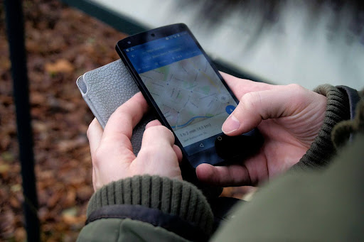 Hands holding a smartphone with a map application open on the screen